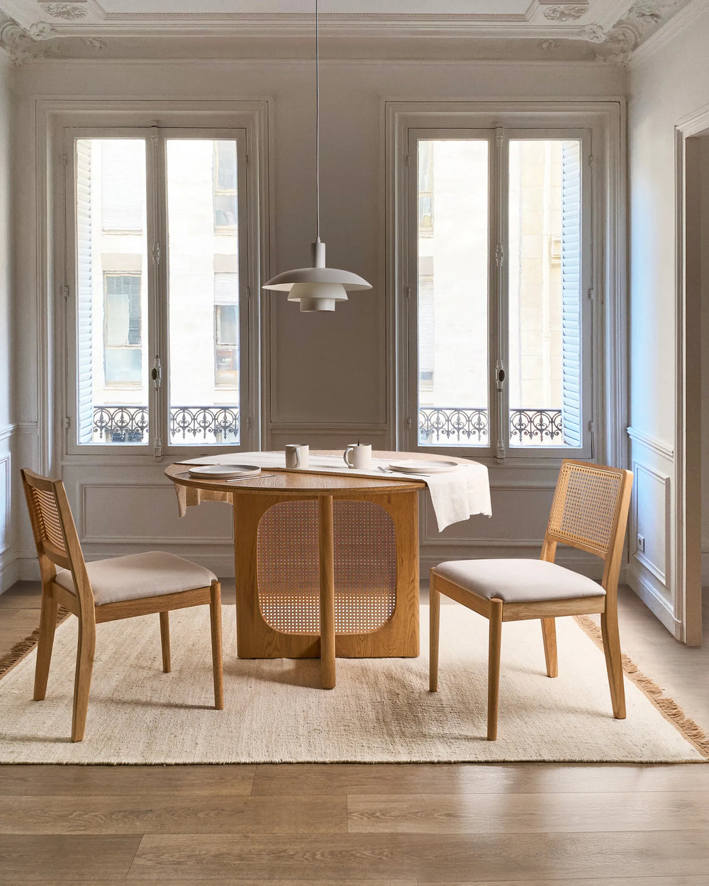 Cane-back dining chairs styled in a bright, elegant dining room with soft neutrals, warm oak tones, and natural light, creating an airy Scandinavian, Japandi, and Parisian-inspired atmosphere.