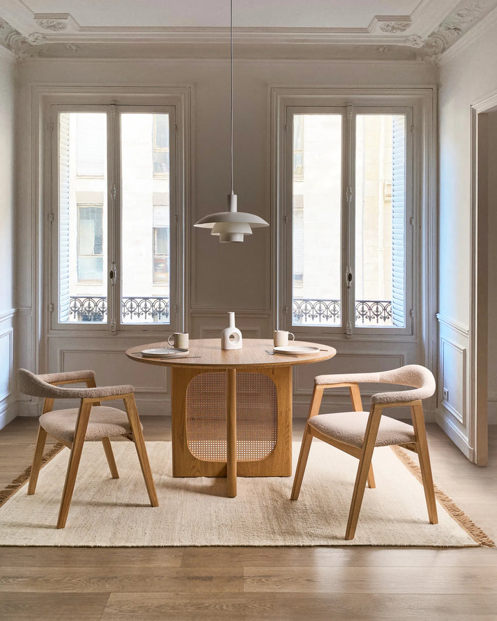 Light wood boucle accent chairs around a wooden dining table in a bright modern dining room.