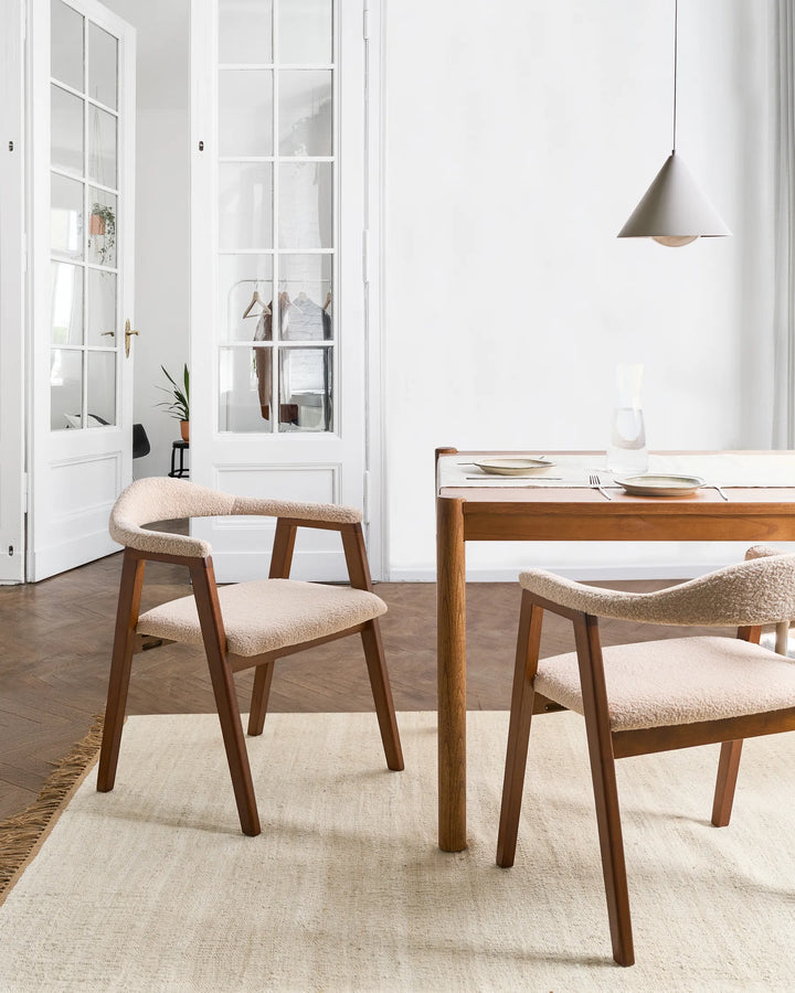Dark wood boucle accent chairs around a wooden dining table in a bright modern dining room.