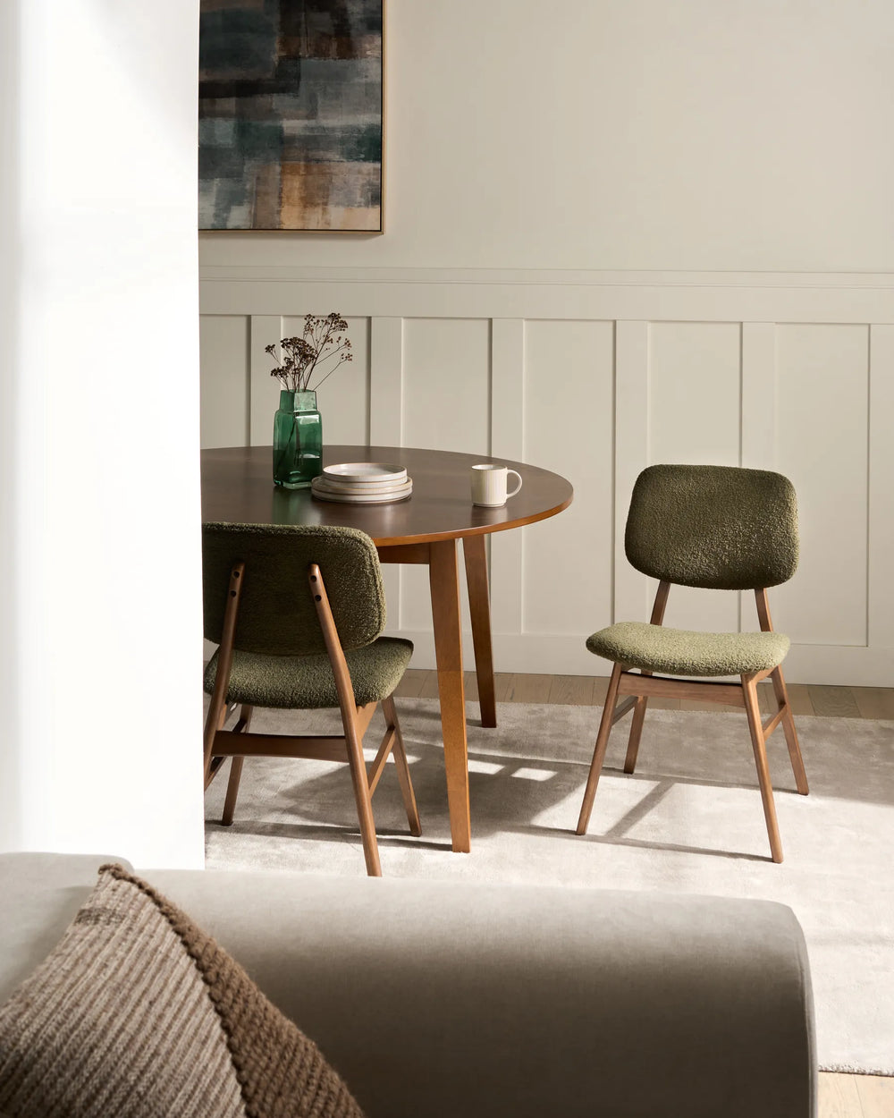 Warm and inviting dining space featuring olive bouclé chairs and rich wood accents, creating a cozy mid-century modern atmosphere.