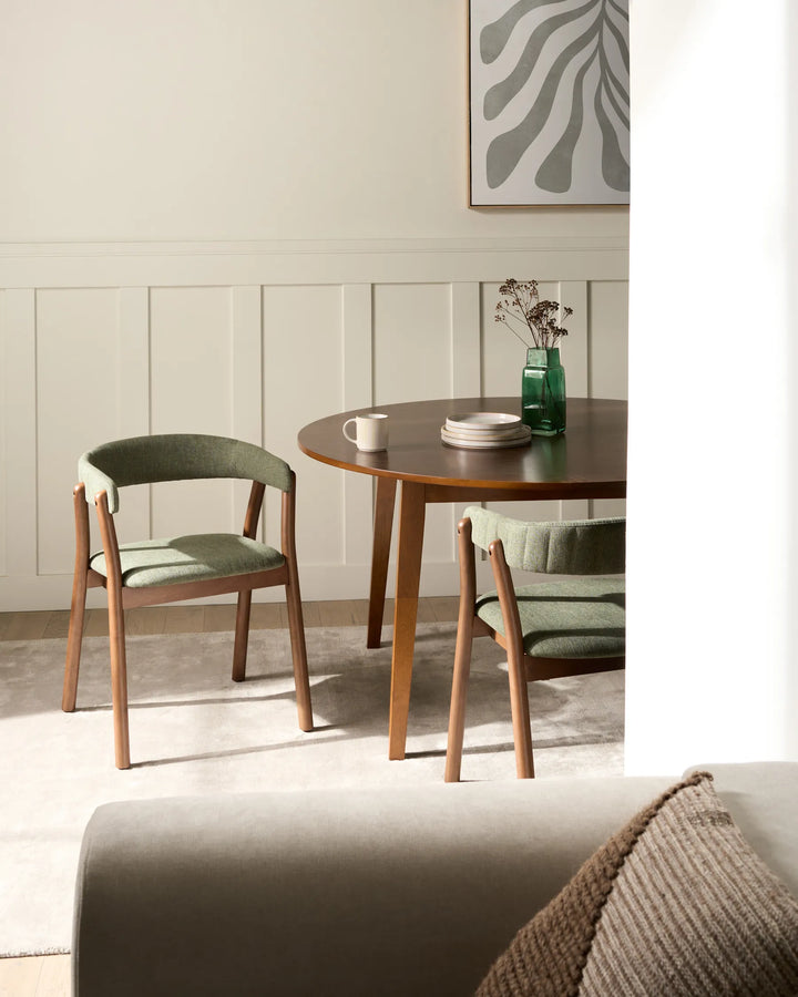 Modern dining space featuring elegant green-upholstered chairs that add natural warmth and refined comfort.