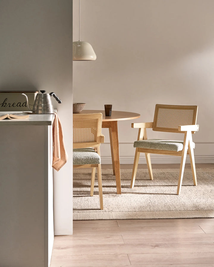 Light wood dining chairs with woven cane backrests and grey boucle seats around a wooden dining table in a modern dining room.
