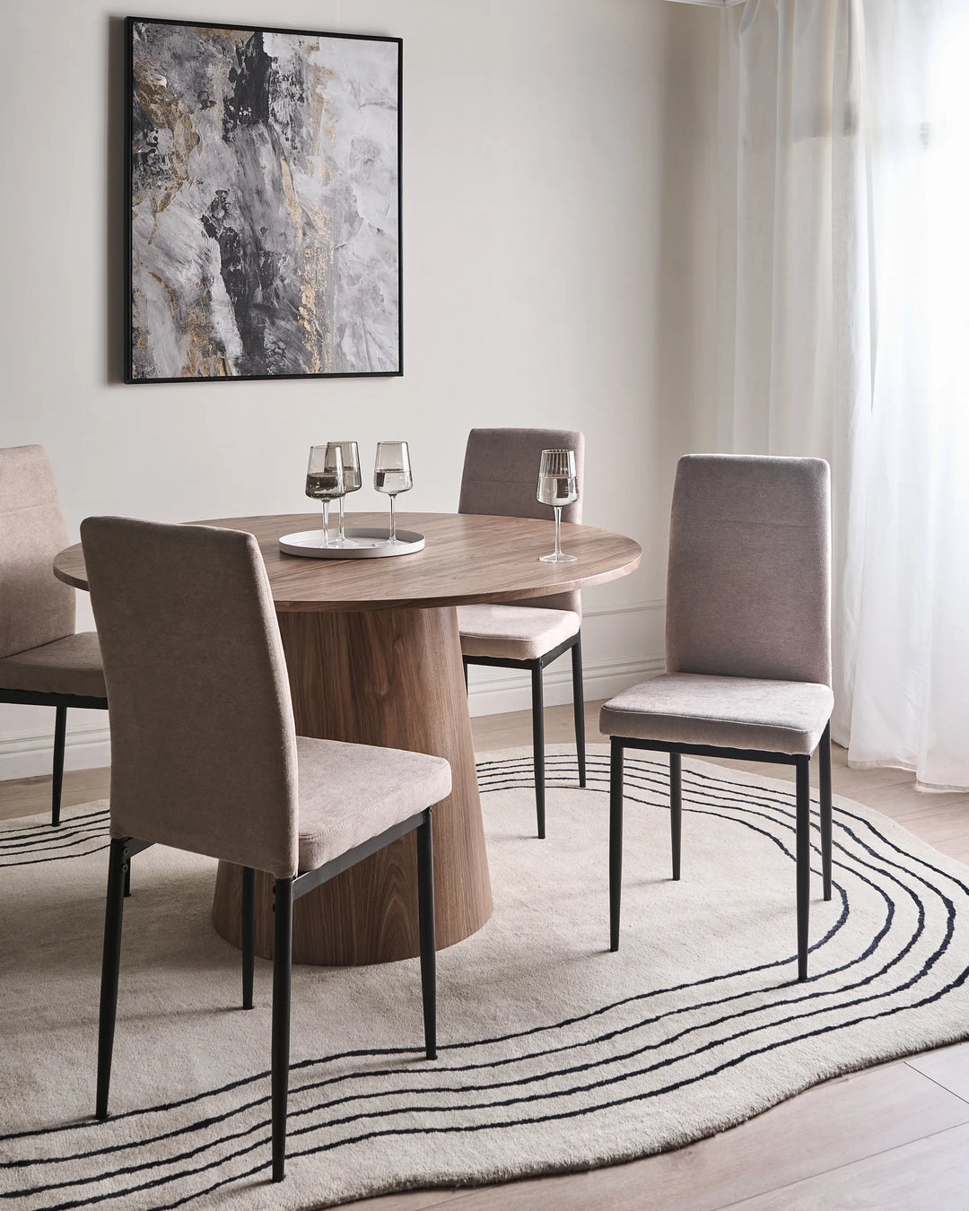 Taupe dining chairs around a round wood table in a modern dining room with soft neutral tones.