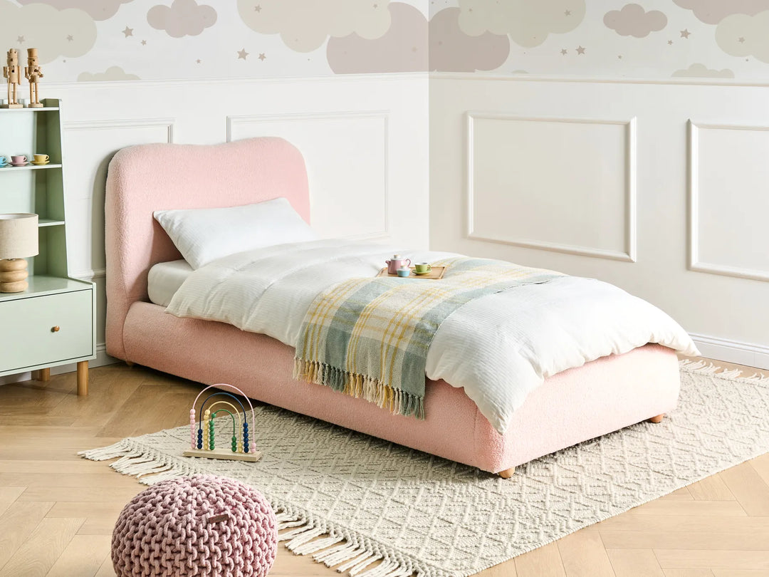 Children's bedroom with a pink bed, white nightstand, and decorative elements.