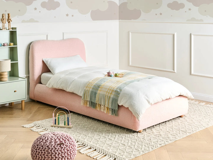 Children's bedroom with a pink bed, white nightstand, and decorative elements.