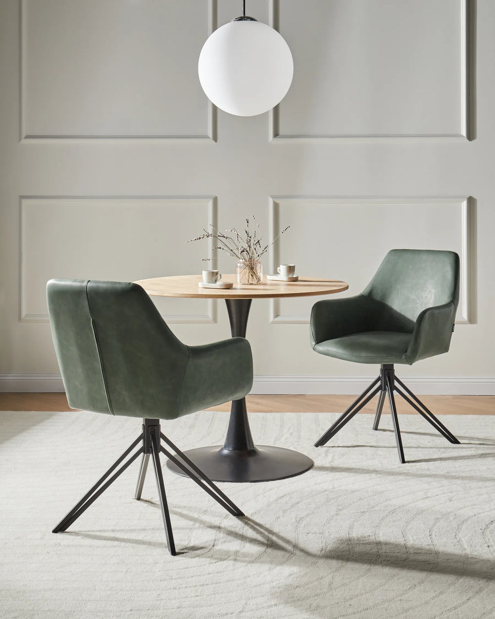 Modern dining setting featuring the chair’s green faux leather upholstery, swivel design, and sleek black metal base.