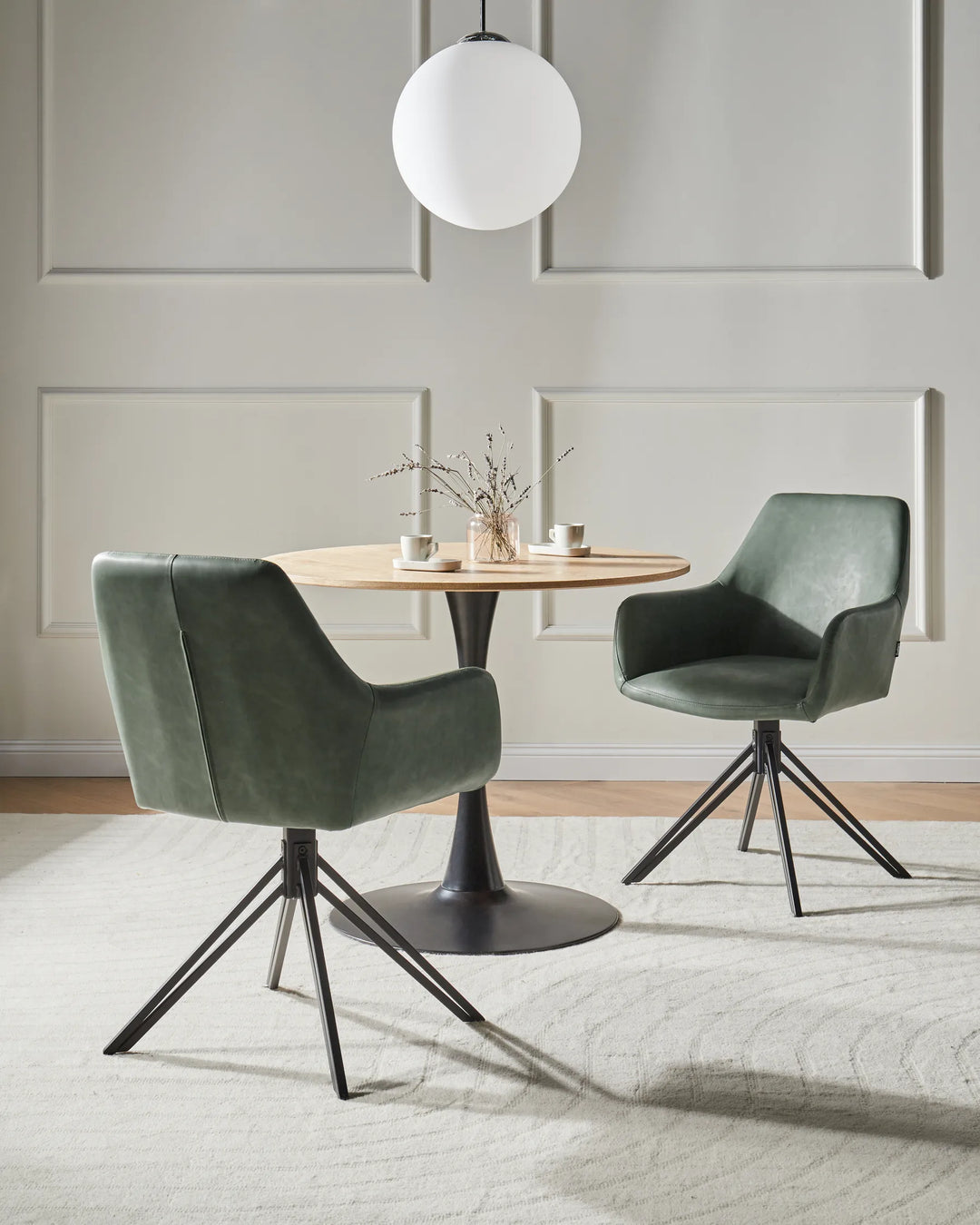 Modern dining setting featuring the chair’s green faux leather upholstery, swivel design, and sleek black metal base.