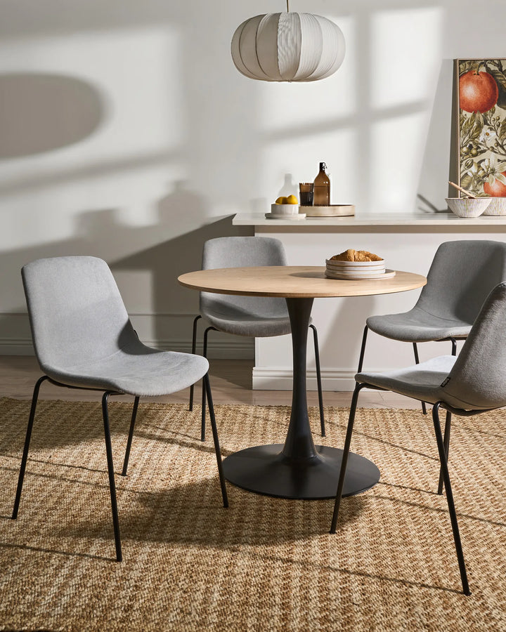 Light grey velvet dining chairs around a round wood dining table.