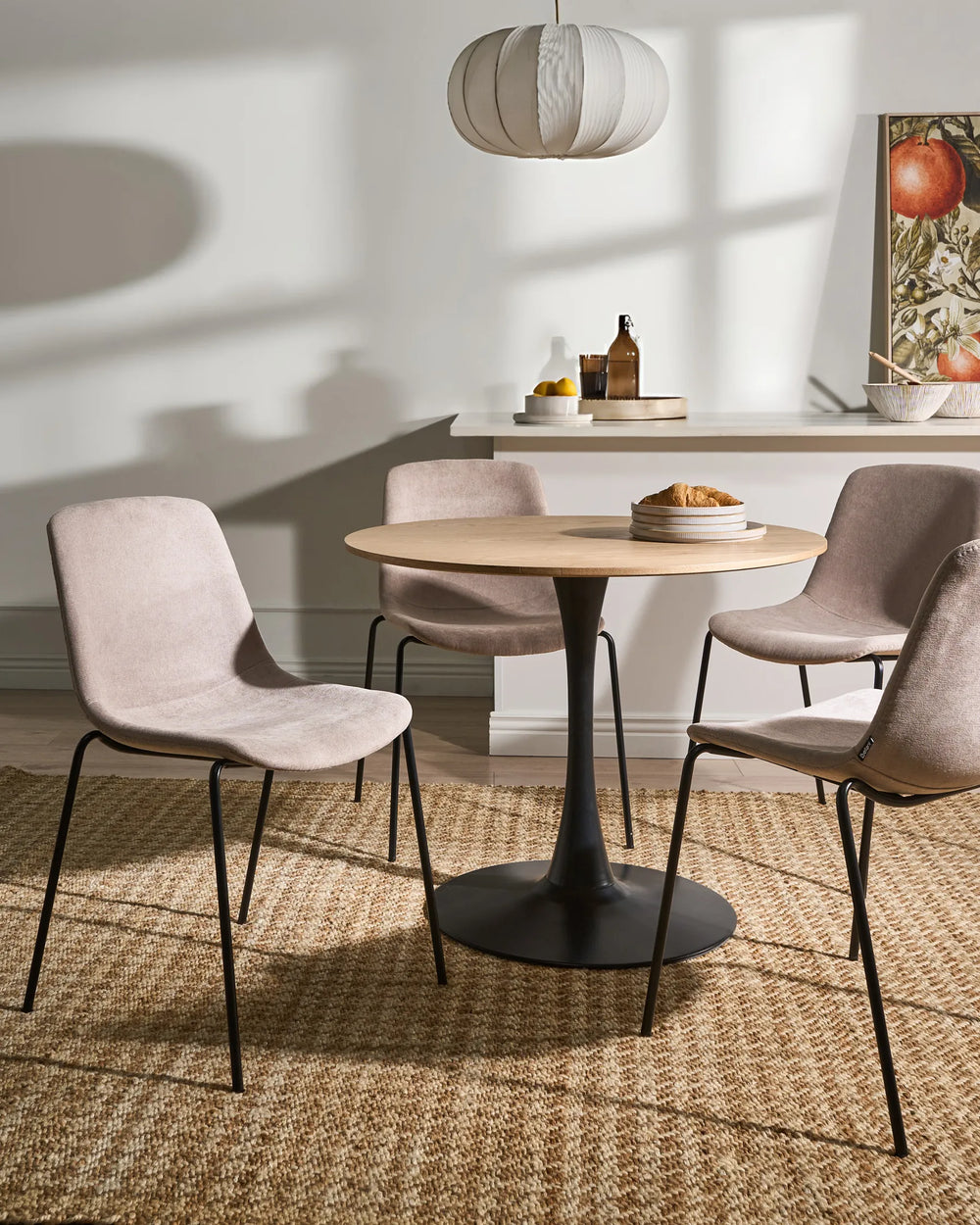 Beige velvet dining chairs around a round wood dining table.