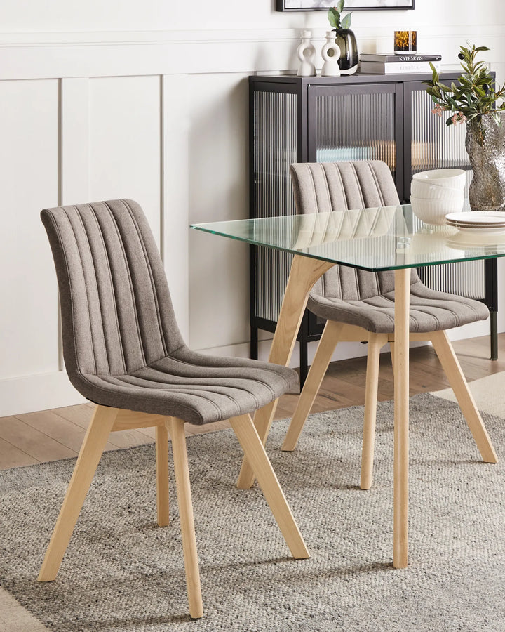 Scandinavian-inspired dining area featuring upholstered chairs with wooden legs, paired with a glass-top table for a clean, contemporary look.