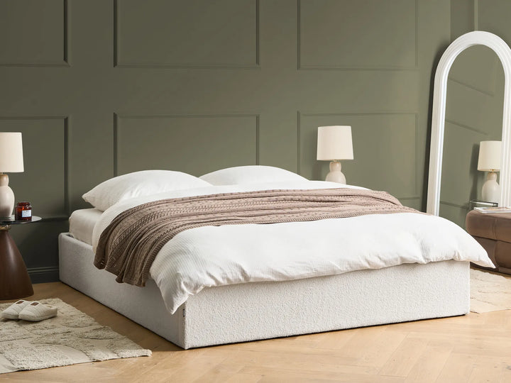 Neatly made bed with white bedding and a brown throw blanket in a bedroom setting.