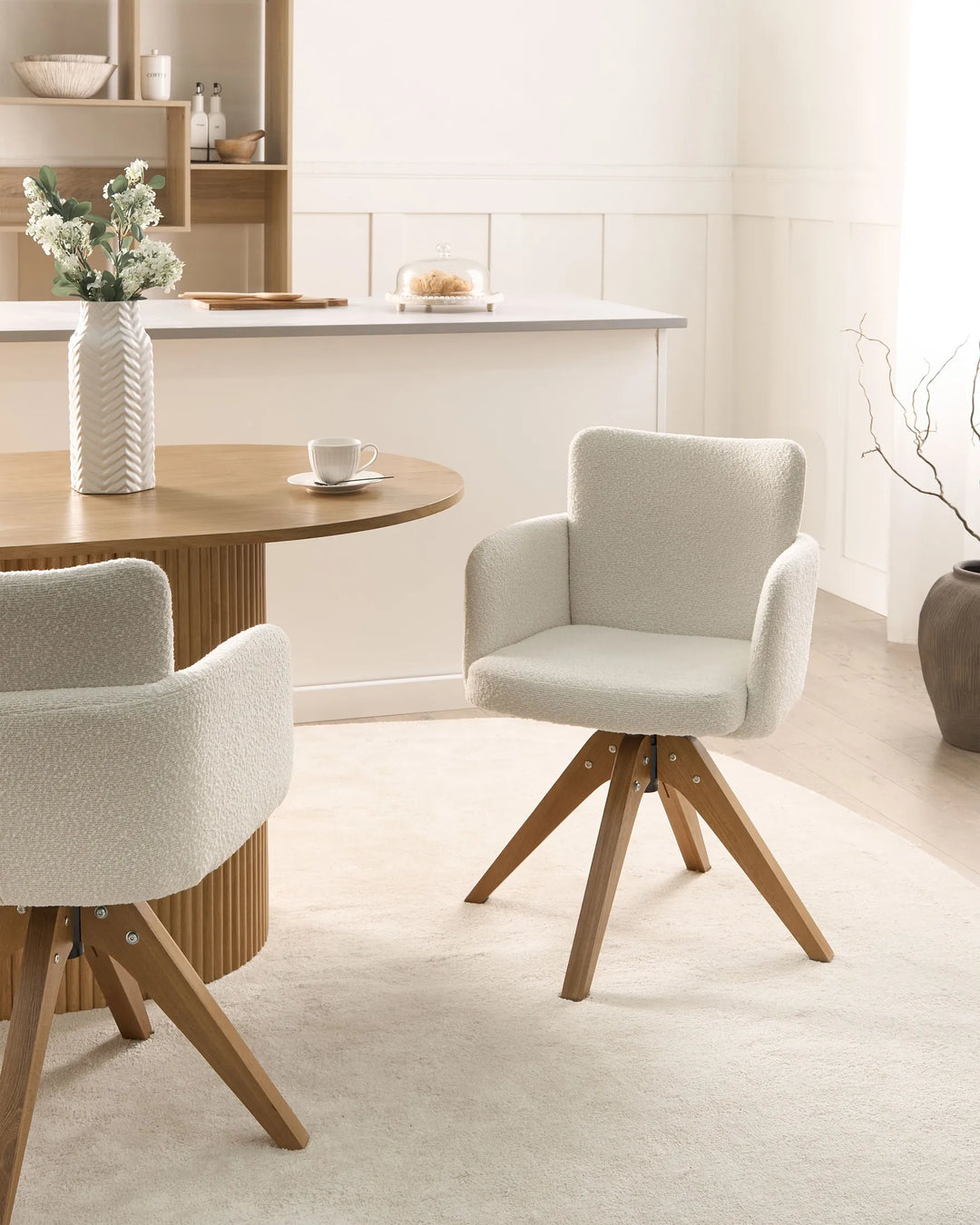 Cream bouclé dining chair styled in a bright, modern dining space with warm wood accents.