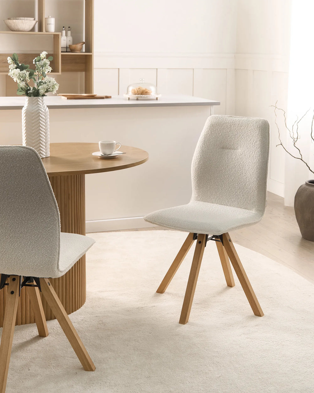 Light and airy dining space featuring bouclé chairs and oak accents, creating a cozy, modern atmosphere.