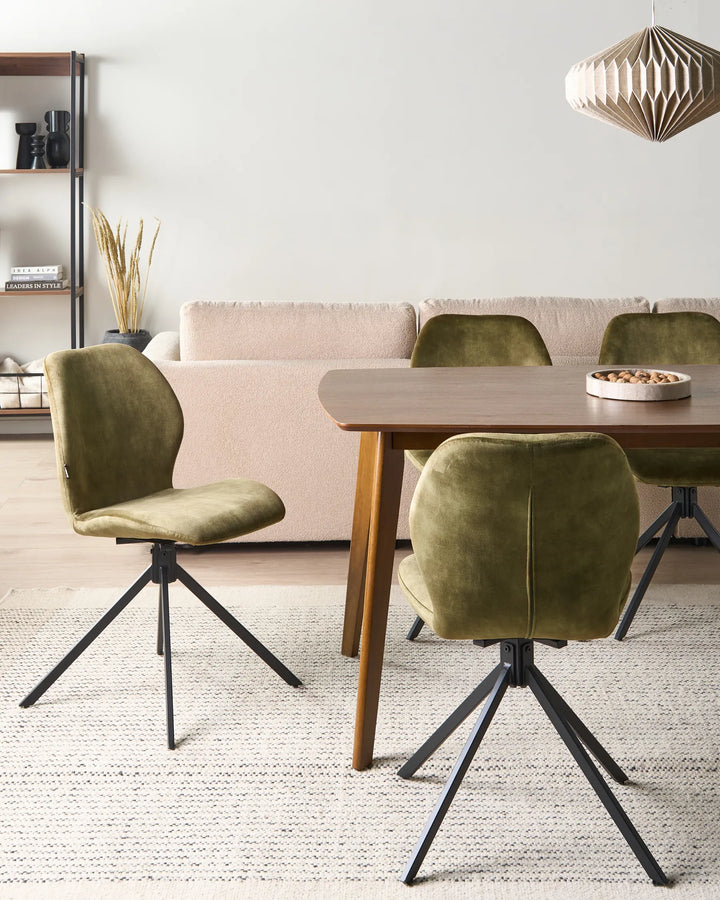 Olive velvet swivel dining chairs around a walnut dining table with a beige sofa and cream rug.