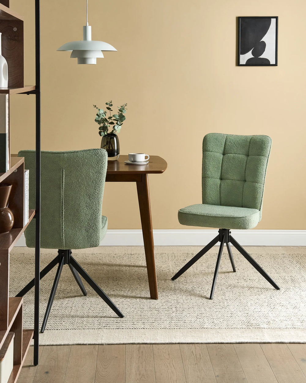 Light green bouclé swivel dining chairs around a walnut dining table with a vase, coffee cup, pendant light, shelving, and a cream rug.