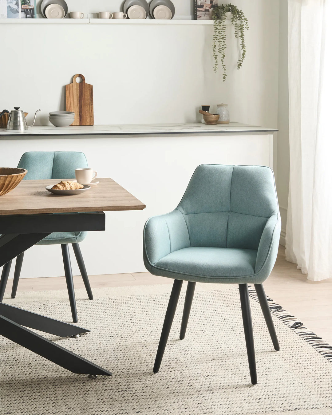 Light blue upholstered dining chairs around a wooden dining table in a bright, modern dining room with minimalist décor and natural light.