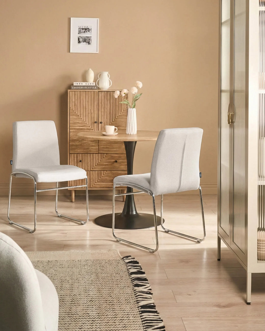 Light grey fabric dining chairs with chrome legs arranged around a dining table in a contemporary dining space with minimalist décor.