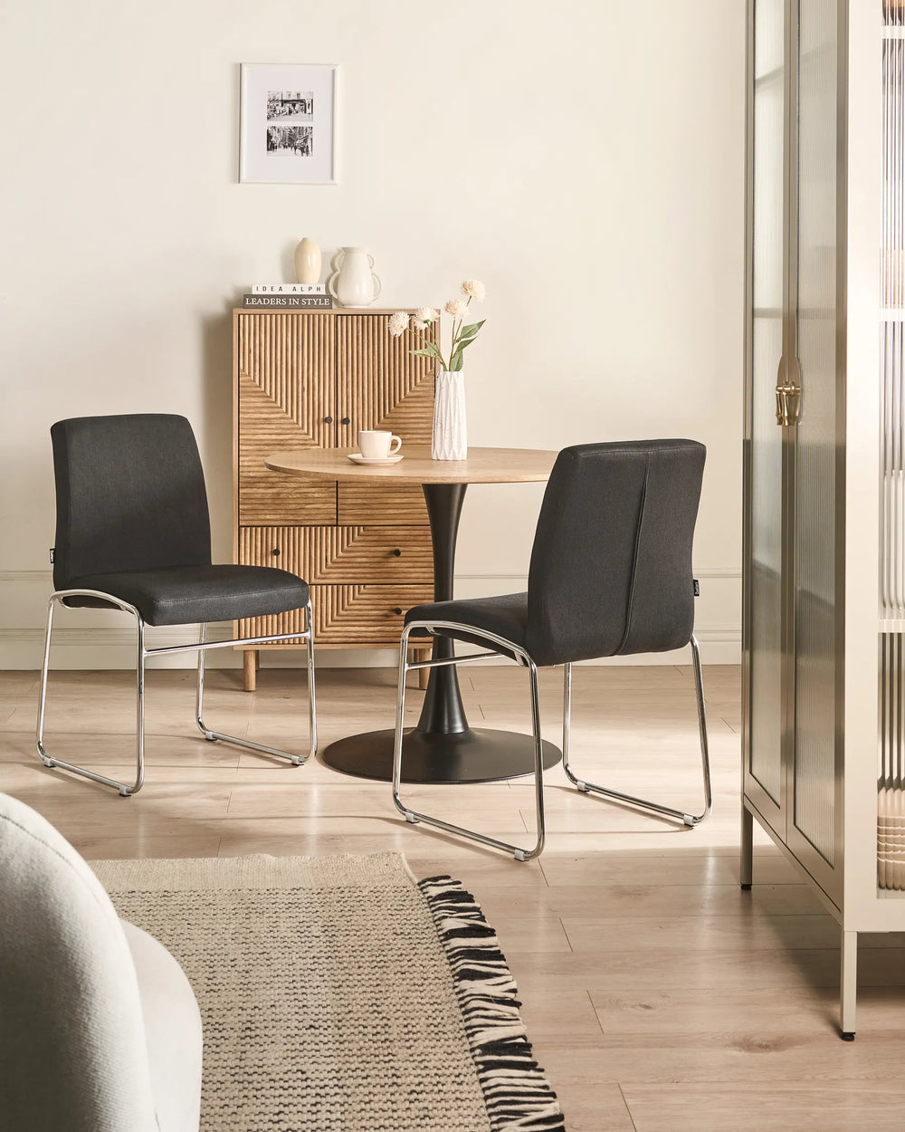 Black fabric dining chairs with chrome legs arranged around a dining table in a contemporary dining space with minimalist décor.