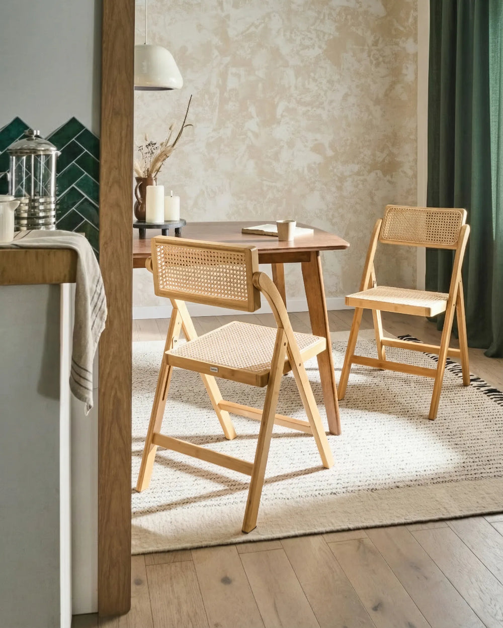 Natural wood folding cane chairs styled around a dining table in a warm, cozy dining space with textured walls, soft lighting, neutral rugs, and earthy décor accents.