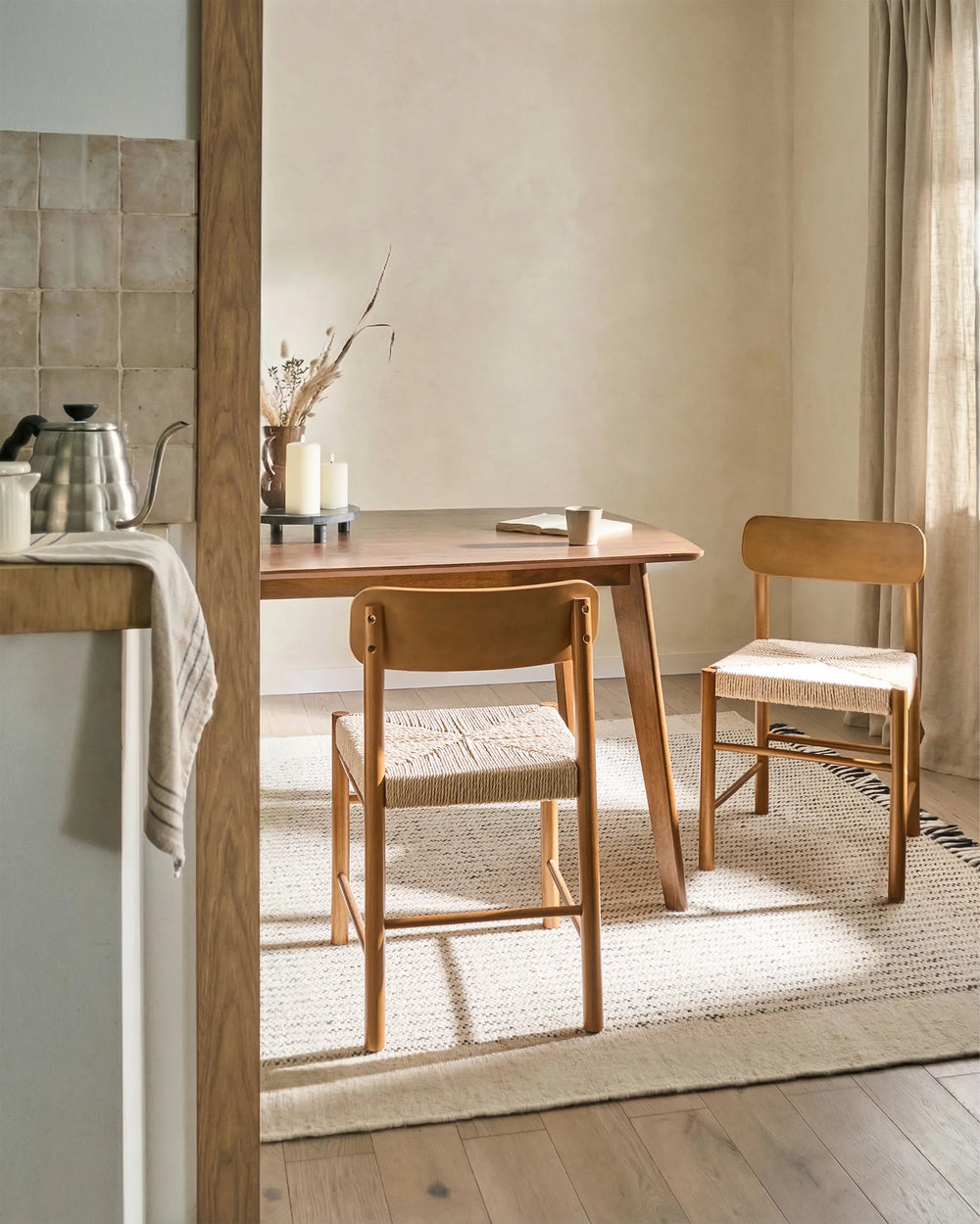 Light wood woven-seat dining chairs styled in a warm, earthy dining setting with soft neutral tones, natural textures, and sunlit accents, creating a cozy Scandinavian, Japandi-inspired atmosphere.