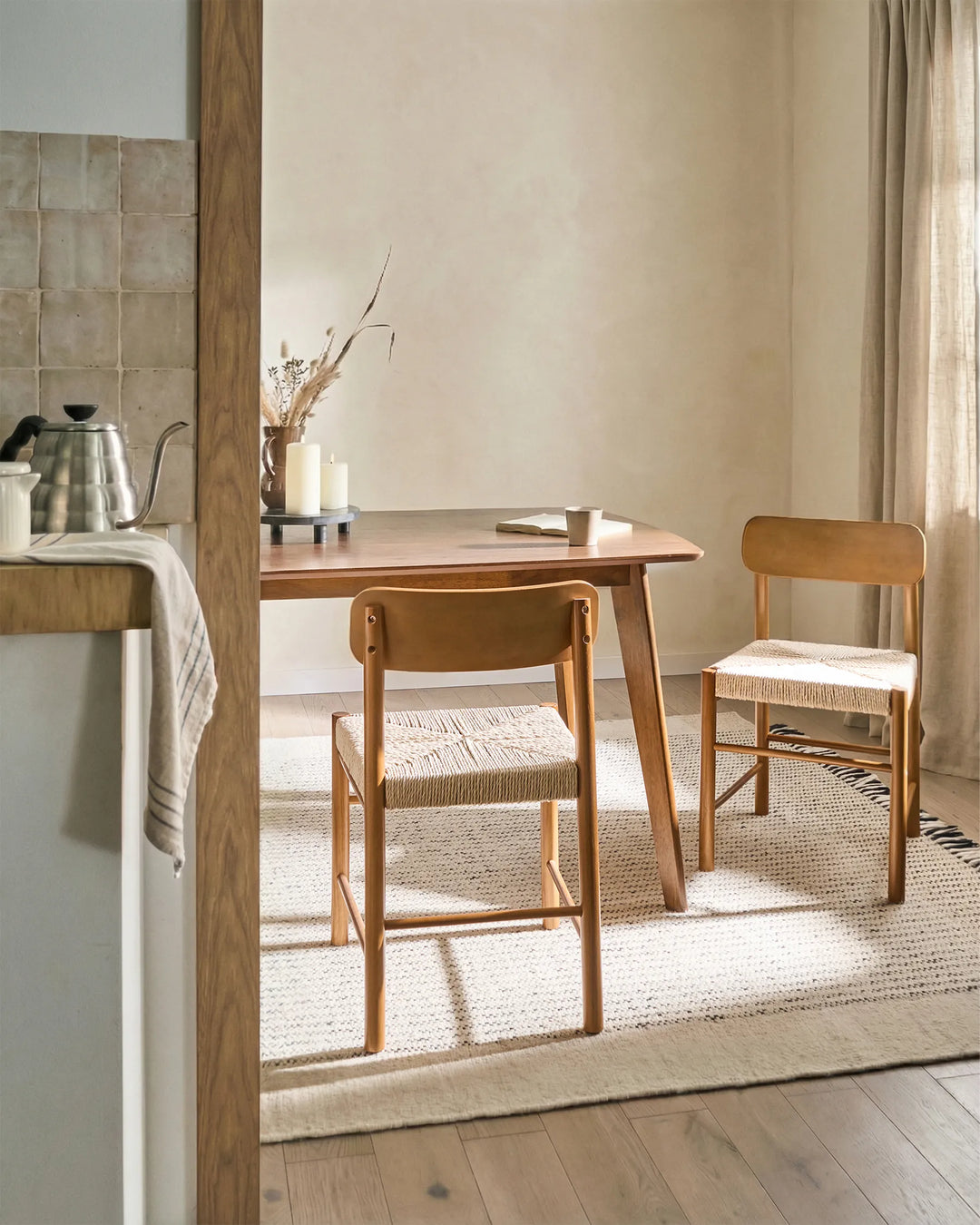 Light wood woven-seat dining chairs styled in a warm, earthy dining setting with soft neutral tones, natural textures, and sunlit accents, creating a cozy Scandinavian, Japandi-inspired atmosphere.