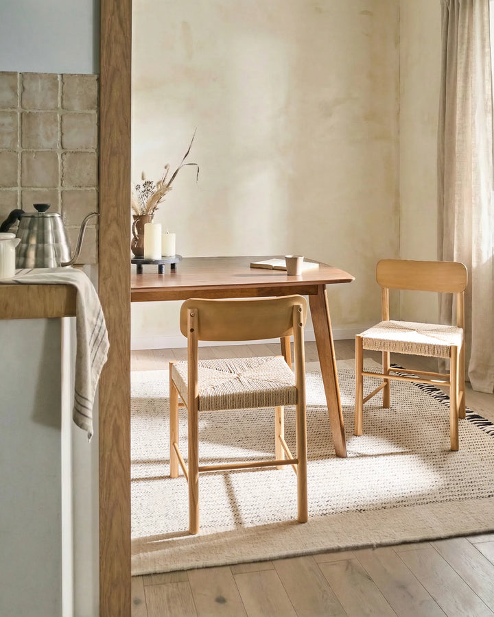 Natural wood woven-seat dining chairs styled in a warm, organic dining space with soft neutral tones, textured textiles, and minimalist décor, creating a cozy Scandinavian-inspired and earthy atmosphere.