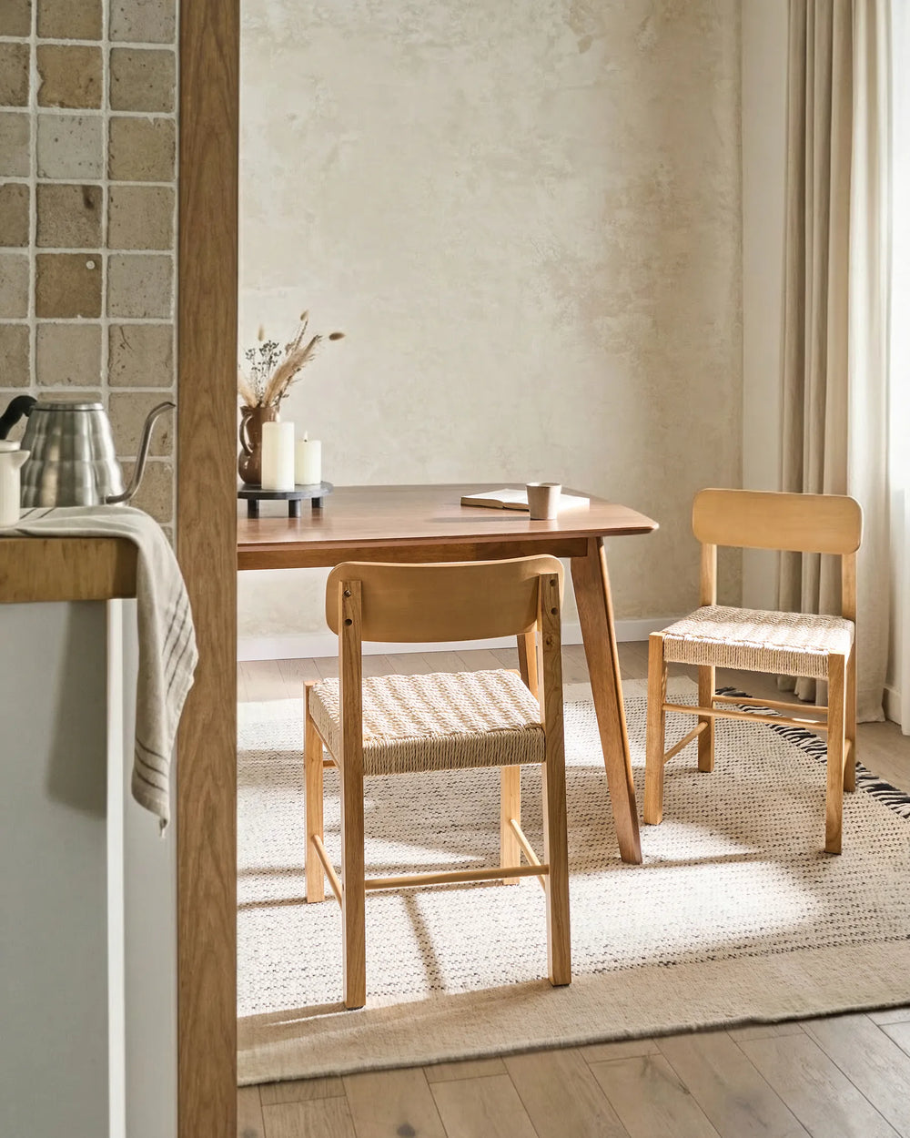Natural wood woven dining chairs styled in a bright, cozy dining space with soft textures and warm neutral tones, creating an airy, inviting, and relaxed atmosphere.