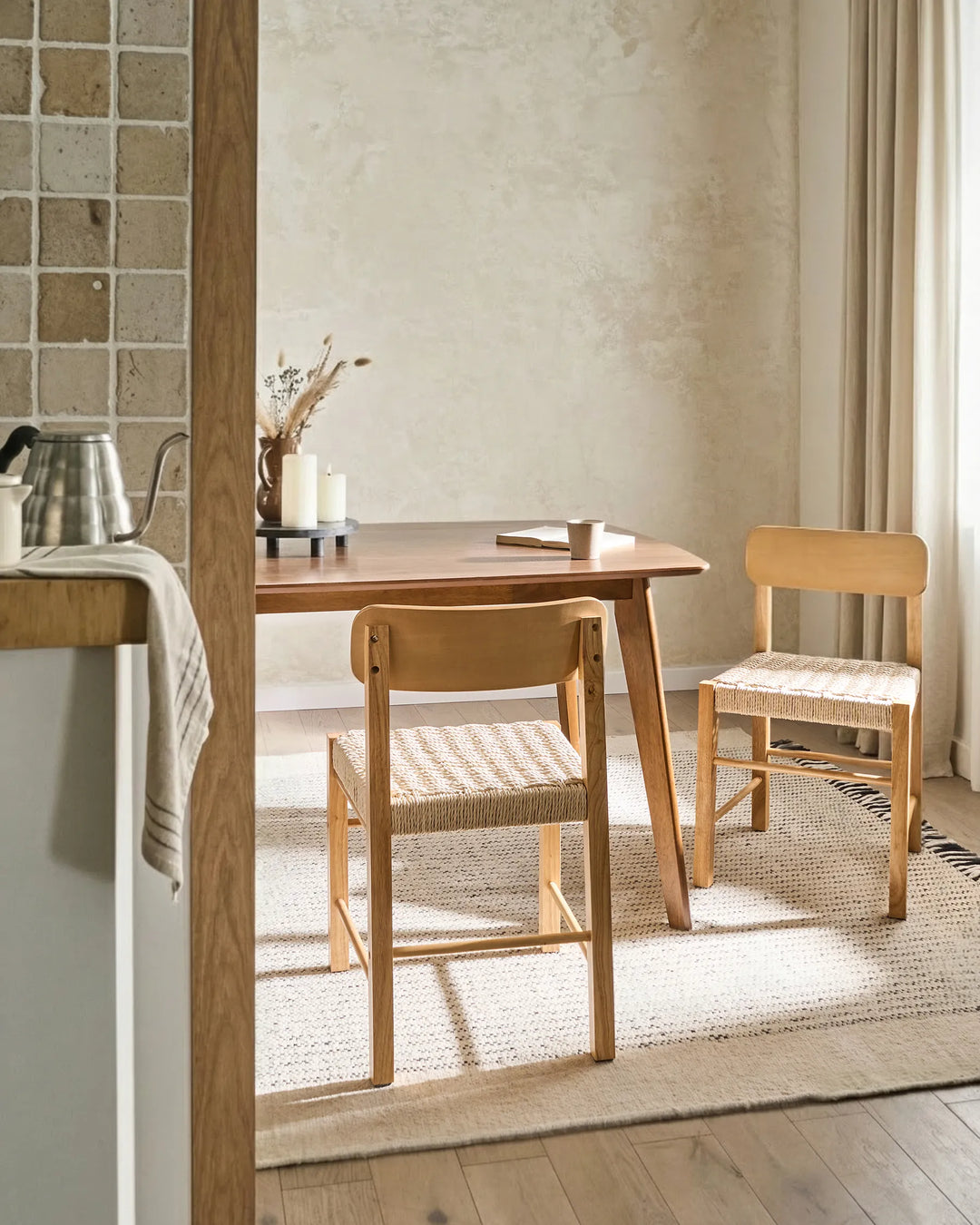 Natural wood woven dining chairs styled in a bright, cozy dining space with soft textures and warm neutral tones, creating an airy, inviting, and relaxed atmosphere.