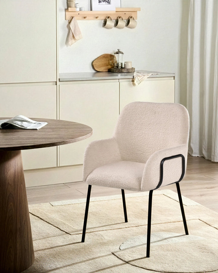 Light beige bouclé dining chairs with rounded backrests and black metal legs arranged around a dining table in a bright, modern dining space with minimalist décor.