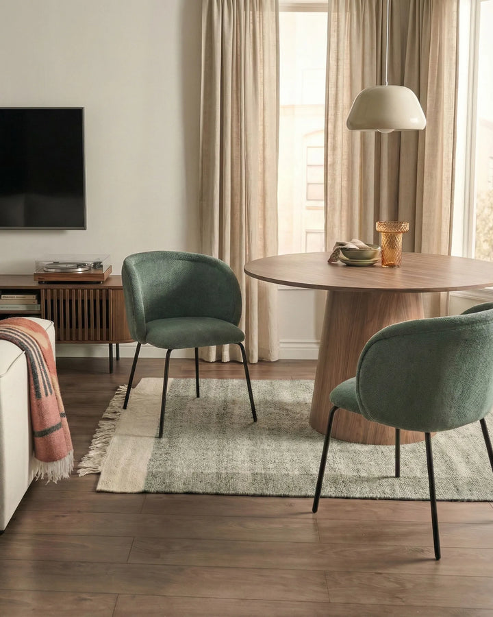 Green dining chairs styled around a wood dining table in a warm, modern living and dining space.