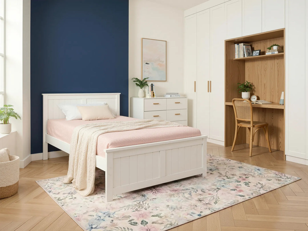 White pine wood bed frame with a simple design, placed in a bright modern bedroom with minimal furniture and neutral decor in the background.