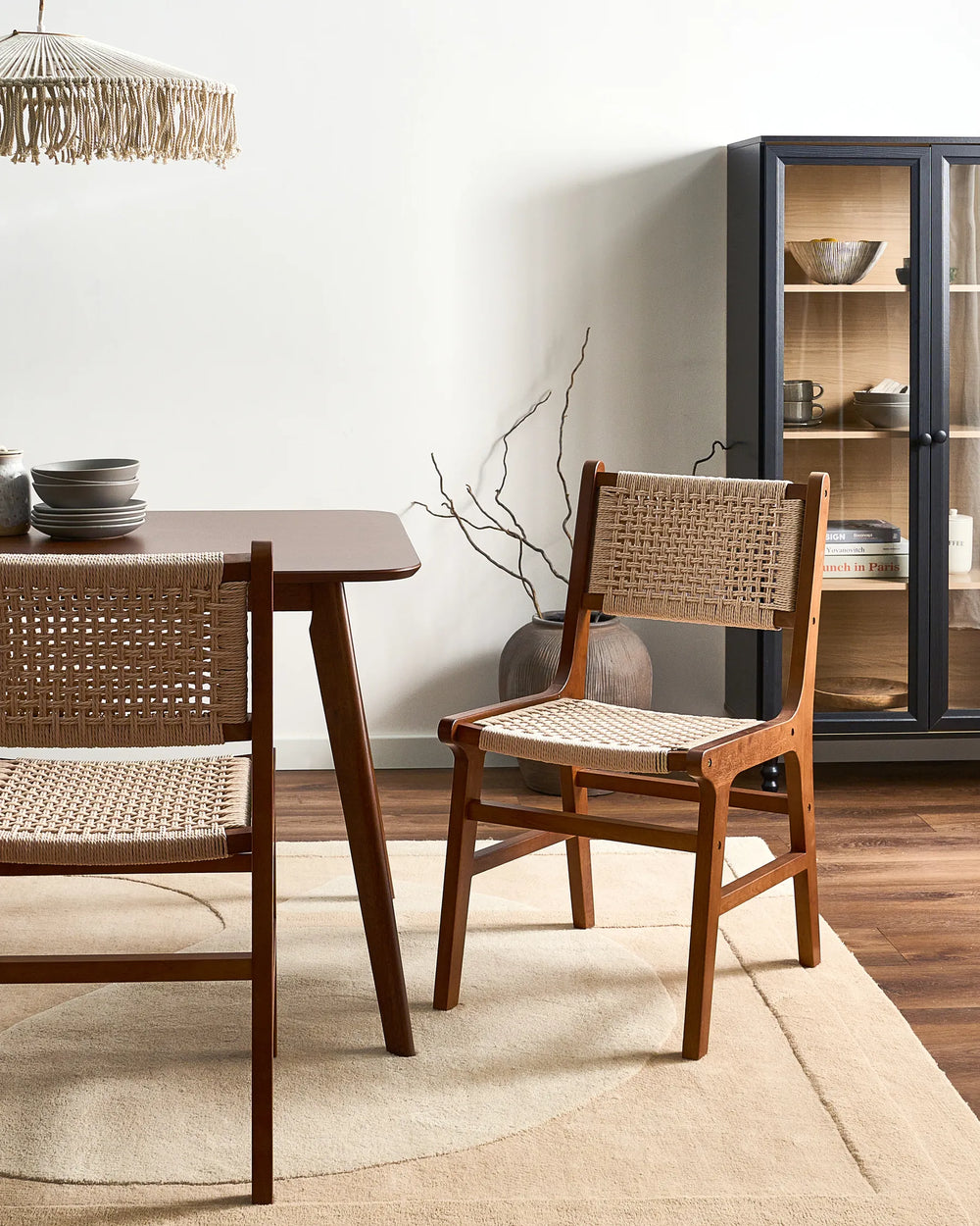 Dark wood woven rope dining chairs around a wooden dining table in a modern dining room.