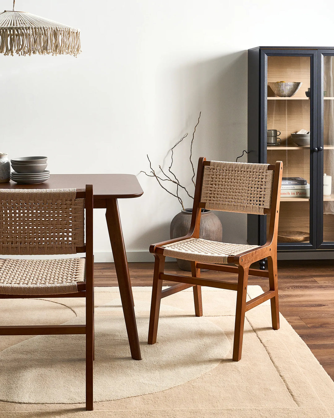 Dark wood woven rope dining chairs around a wooden dining table in a modern dining room.