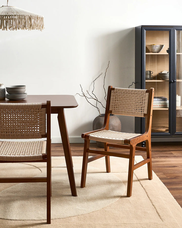Dark wood woven rope dining chairs around a wooden dining table in a modern dining room.