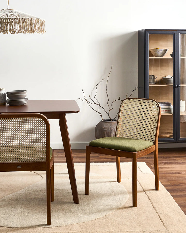 Warm dining setting featuring rattan dining chairs with green seats and rich wood tones, creating a cozy and sophisticated atmosphere.