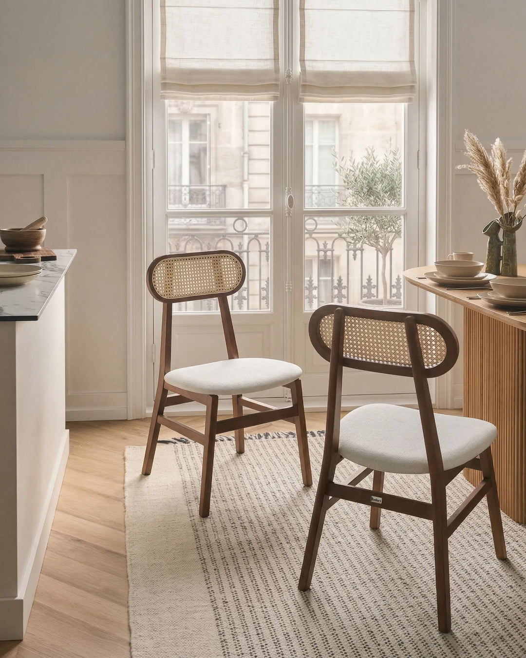 Dark wood cane-back dining chairs styled around a dining table in a warm, elegant dining space with soft natural light, neutral tones, textured rug, and cozy minimalist décor.