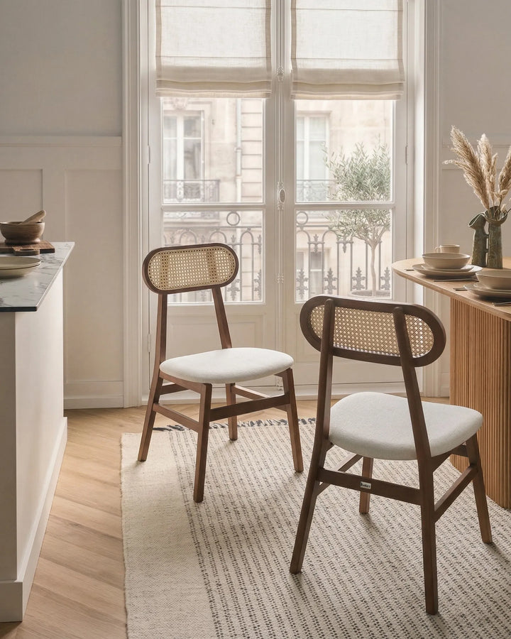 Dark wood cane-back dining chairs styled around a dining table in a warm, elegant dining space with soft natural light, neutral tones, textured rug, and cozy minimalist décor.