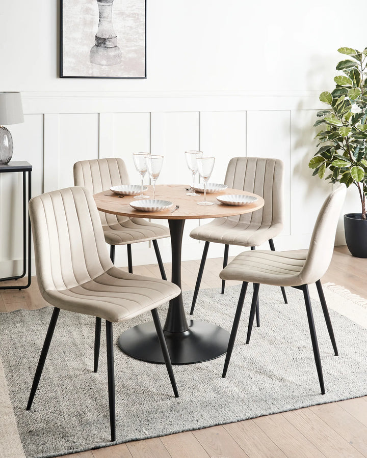 Modern dining setup featuring elegant beige velvet chairs, a round pedestal table, and clean contemporary styling.