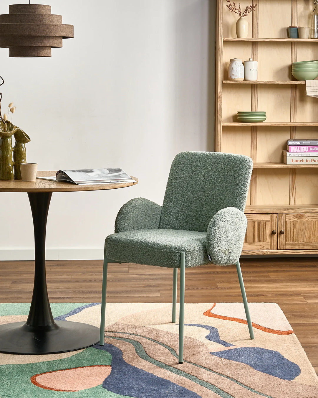 Modern dining space featuring the sage-green bouclé chair, natural wood furniture, and warm contemporary décor.