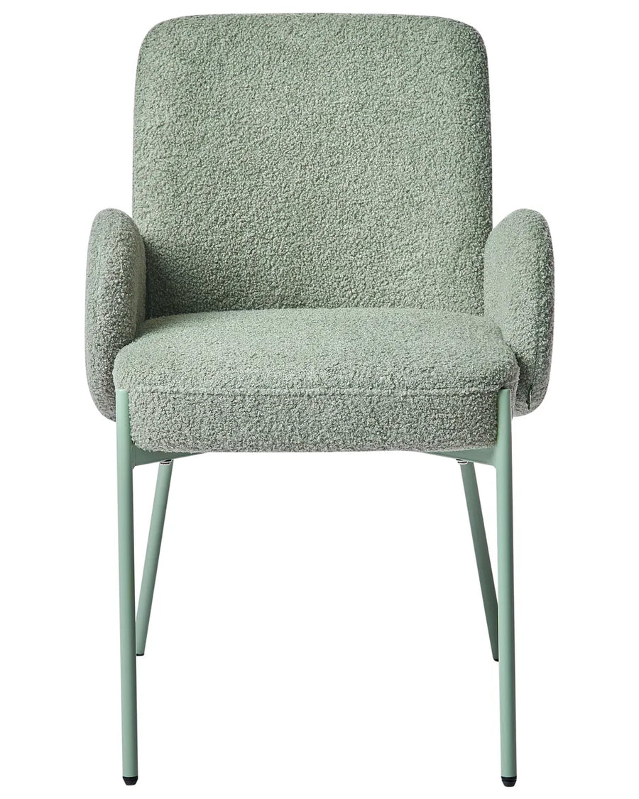 Sage-green bouclé dining chair with rounded armrests, cushioned seat, and matching metal legs.