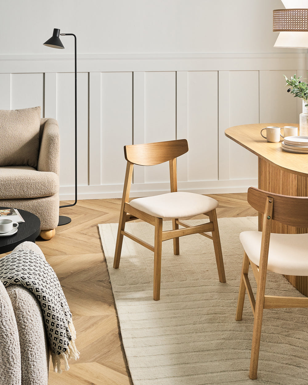 Contemporary Scandinavian dining chair styled in a warm, cozy dining space with light wood finishes, textured fabrics, soft neutral tones, and minimalist décor for an inviting modern-home feel.