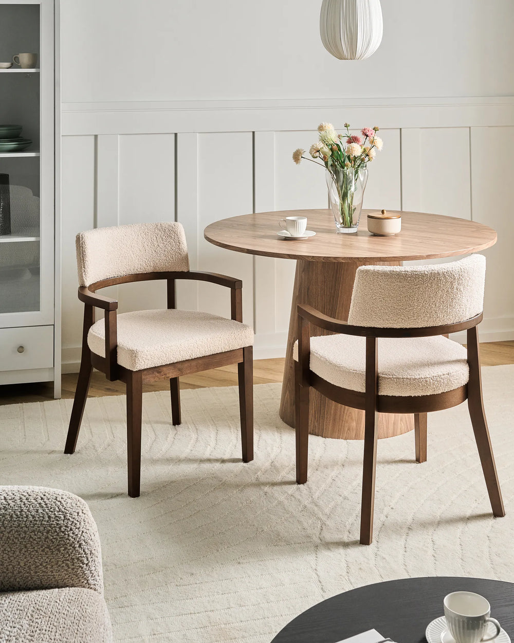 Modern dining space featuring bouclé chairs and a round wood table, creating a cozy and elegant atmosphere.