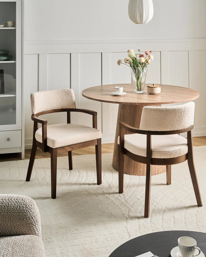 Modern dining space featuring bouclé chairs and a round wood table, creating a cozy and elegant atmosphere.