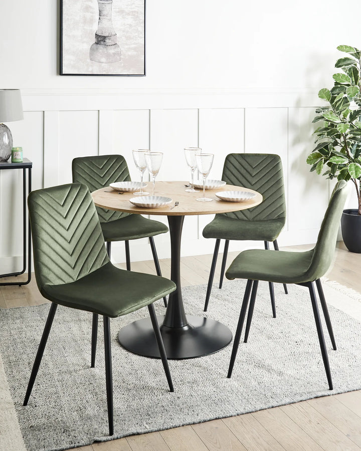 Set of green velvet dining chairs styled around a round dining table in a bright contemporary dining room.