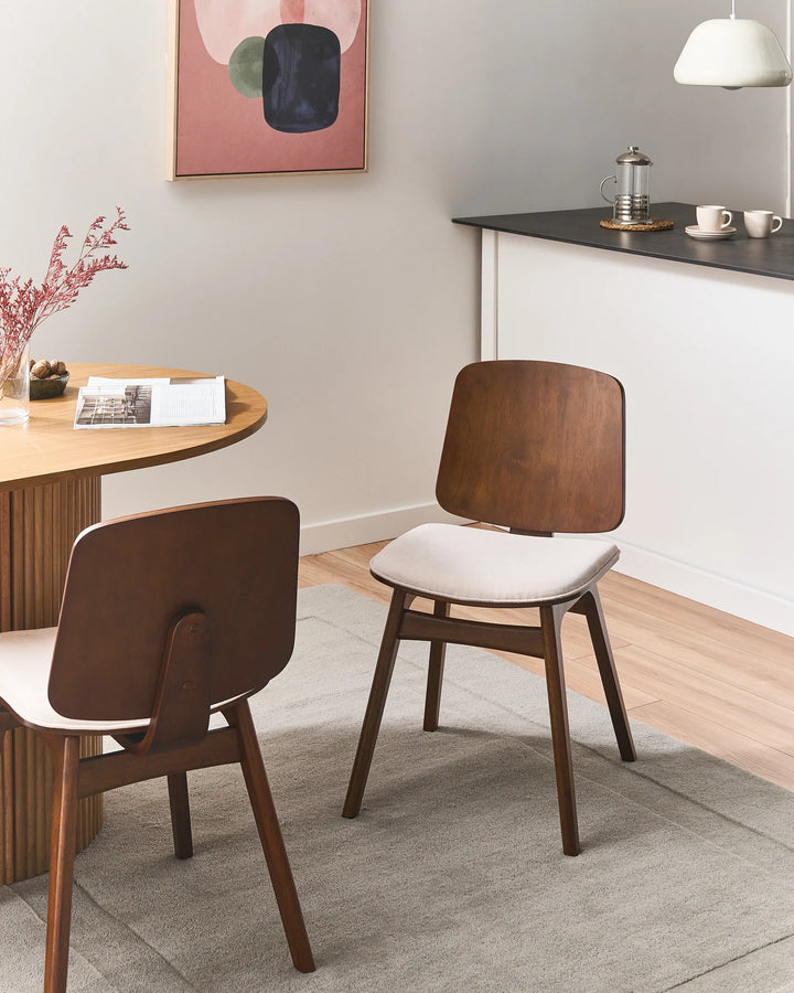 Walnut dining chairs styled in a cozy, contemporary dining space, blending warm wood tones, soft upholstery, and minimalist décor for an elegant everyday dining atmosphere.