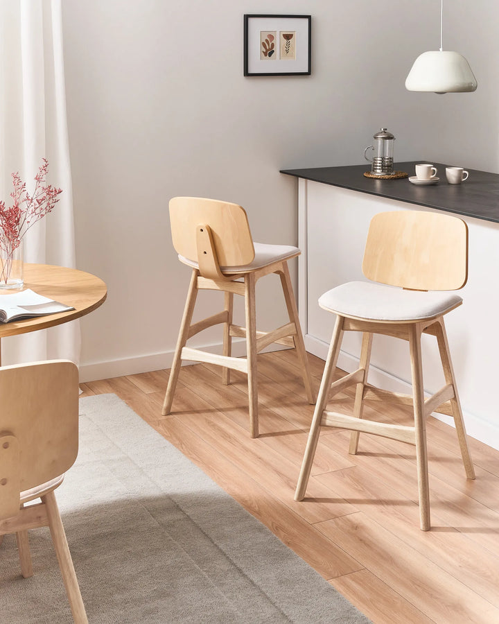 Light wood counter stools styled in a warm, minimalist kitchen-dining space, combining soft neutral tones, natural textures, and contemporary simplicity for an inviting everyday setting.