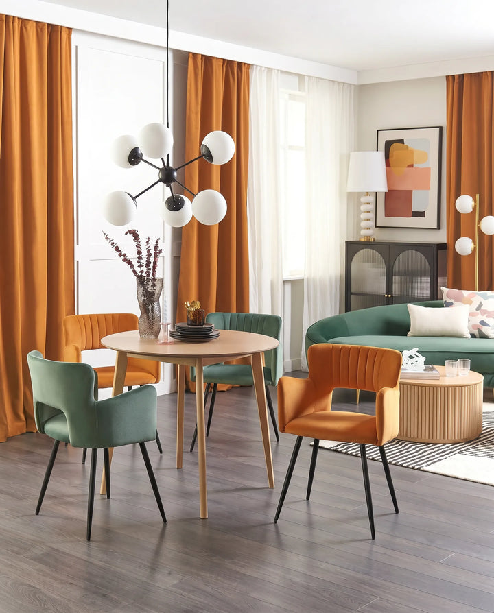 Contemporary dining space featuring mustard and green velvet chairs, creating a vibrant and stylish atmosphere.