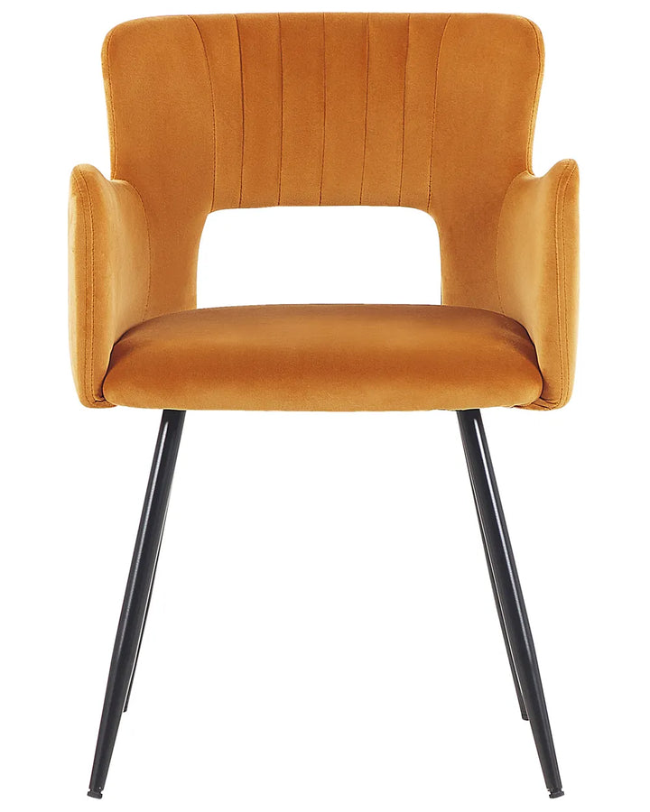 Mustard velvet dining chair with a curved open-back design, padded armrests, and black metal legs for a bold modern look.