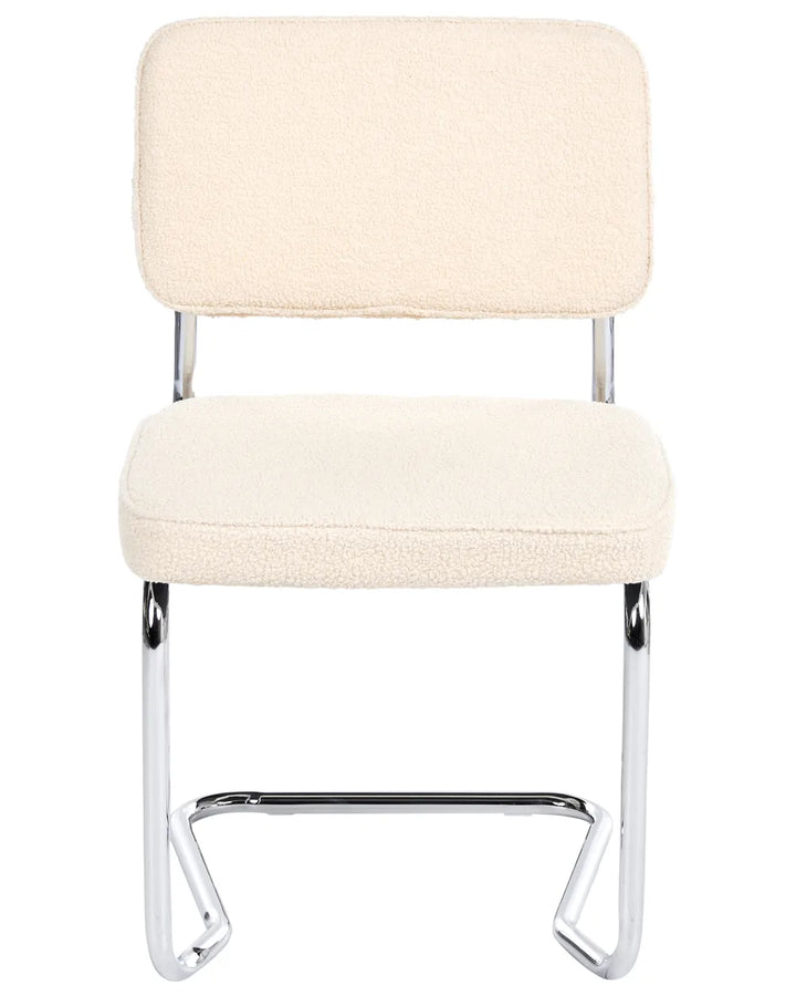 Light beige bouclé cantilever dining chair without armrests, with an upholstered seat and backrest, on a silver-tone metal frame.