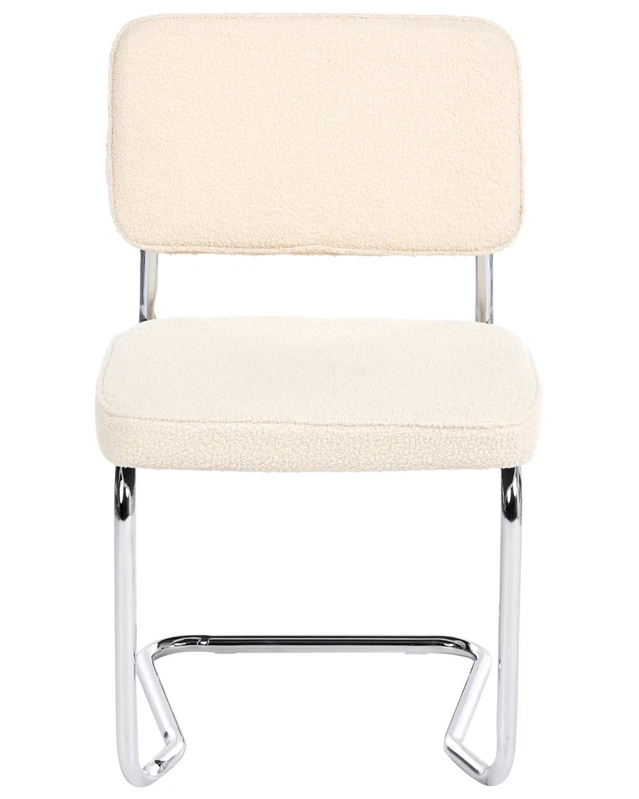 Light beige bouclé cantilever dining chair without armrests, with an upholstered seat and backrest, on a silver-tone metal frame.